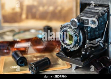 Eine alte Kamera sitzt auf einer Holzoberfläche, umgeben von alten Fotos, die Erinnerungen an vergangene Momente und Geschichten wecken. Stockfoto