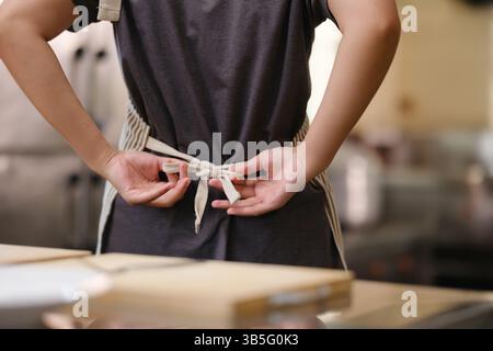 Nahaufnahme von Koch, der Schürze bindet Stockfoto