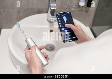 Posen, Polen – 27. April 2025: Die elektrische Zahnbürste Laifen Wave und die App zur Steuerung des Smartphones über dem Waschbecken im Badezimmer, die den Moder repräsentiert Stockfoto