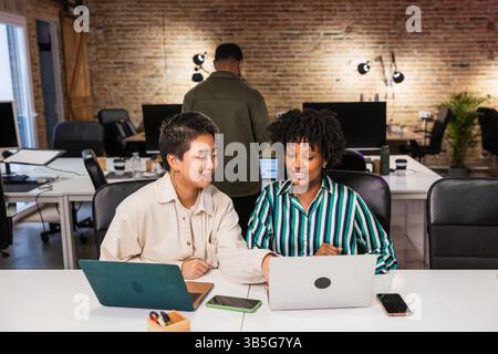 Multiethnisches Team arbeitet gemeinsam an Projekten mit Laptops in modernen Büros Stockfoto