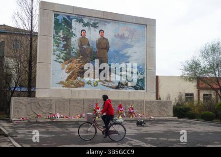 14. April 2017: Eine Frau fährt ihr Fahrrad vor einem öffentlichen Wandgemälde mit KIM JONG-SUK (links) und KIM IL SUNG (rechts) in der Stadt Sariwon, der Hauptstadt der nordkoreanischen Provinz Hwanghae. Radfahren ist eine der wichtigsten Transportmethoden in einem Land, in dem private Fahrzeuge für die meisten Bürger unzugänglich sind. Im Gegensatz zu den anderen Ländern in Nordkorea müssen Bürger einen Führerschein erwerben, müssen ihre Fahrräder registrieren und ein Kennzeichen anbringen, das von den Behörden identifiziert werden kann. (Bild: © Angel Garcia/ZUMA Press Wire) Stockfoto