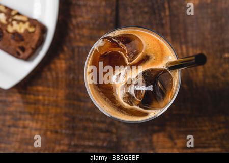 Hohes Glas mit Eis gefüllt, mit Eiskaffee gemischt mit Sahne auf Holztisch Stockfoto