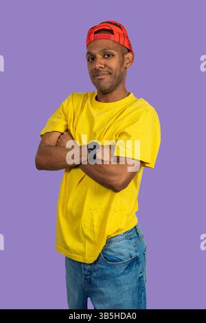 Studio-Porträt eines jungen Mannes, der legere Kleidung mit gekreuzten Armen trägt und Selbstvertrauen und Stil ausstrahlt Stockfoto