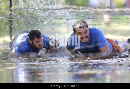Sofia, Bulgarien - 9. Juli 2016: Die Teilnehmer krabbeln bei der extremen Sportwettbewerb Legion Run in der Nähe von Sofia unter elektrifizierten Drähten durch Wasser. Stockfoto