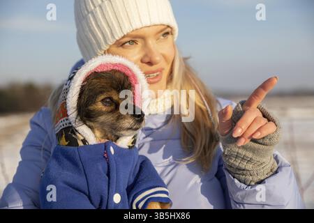 Eine Nahaufnahme des Gesichts der Frau. Sie trägt eine warme Jacke, einen Hut und Handschuhe, die ihre Finger freilegen. Die Frau zeigt mit dem Finger auf etwas. Sie ist ho Stockfoto