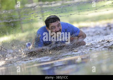Sofia, Bulgarien - 9. Juli 2016: Ein Teilnehmer krabbelt bei der extremen Sportwettbewerb Legion Run in der Nähe von Sofia unter elektrifizierten Drähten durch Wasser. Stockfoto