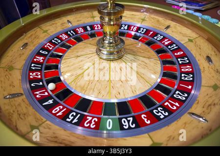 Roulette-Tisch im Kasino. Ball in der rotierenden Spielmaschine. Roulette-Rad aus Holz Stockfoto