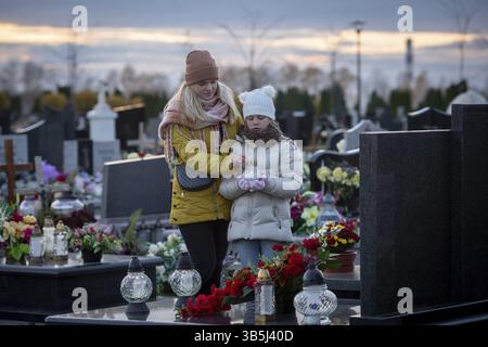 Ein zutiefst berührender und herzlicher Moment zwischen Mutter und Tochter auf einem Friedhof, um ihre verlorenen Angehörigen zu ehren Stockfoto