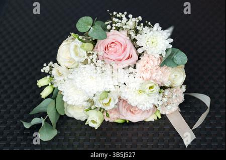 Ein atemberaubender Blumenstrauß mit einer Mischung aus rosa und weißen Rosen, Chrysanthemen und anderen zarten Blüten. Das Arrangement ist wunderschön komponiert und neu Stockfoto