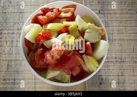 Gurken und Tomaten sallad im weißen Teller auf rustikalen Holztisch Stockfoto