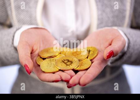 Virtuelle Kryptowährung Geld Bitcoin Goldmünzen in den Händen einer Frau mit rotem nagellack. Die Zukunft des Geldes Stockfoto