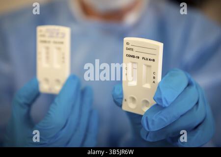Ein negativer COVID-19-Schnelltest ist in der Hand eines medizinischen Fachpersonals zu sehen, das persönliche Schutzausrüstung trägt Stockfoto