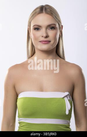 Ein fesselndes Porträt einer eleganten jungen Frau in einem stilvollen grünen Kleid, das Selbstvertrauen und Anmut ausstrahlt Stockfoto