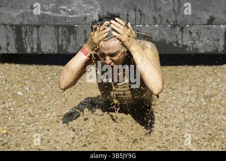 Sofia, Bulgarien - 9. Juli 2016: Ein Teilnehmer taucht im Eiswasser bei der extremen Sportwettbewerb Legion Run in der Nähe von Sofia. Das Sportereignis ist Schlamm Stockfoto