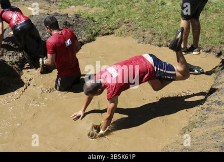 Sofia, Bulgarien - 9. Juli 2016: Die Teilnehmer springen beim Legion Run Extremsport Challenge in der Nähe von Sofia ins matschige Wasser. Die Sportveranstaltung ist mu Stockfoto