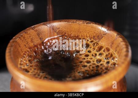 Ein Kaffee wird in einer kleinen Holztasse mit einer Kaffeemaschine zubereitet Stockfoto