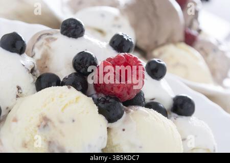 Kugeln Schokoladeneis in die weiße Platte mit Himbeeren und chokeberries Stockfoto