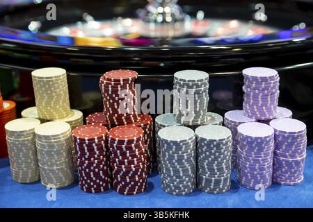Farbenfrohe Roulette-Chips in einem Kasino auf einem Spieltisch in der Nähe des Roulette-Rads. Viele Chips mit verschiedenen Nominierungen und Farben Stockfoto