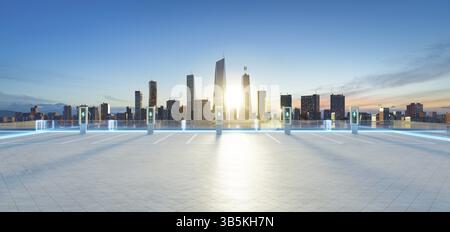 Leerer Parkplatz auf dem Dach mit EV-Ladestationen und leuchtenden Linien, mit Blick auf die moderne Skyline der Stadt bei Sonnenuntergang. 3D-Rendering Stockfoto