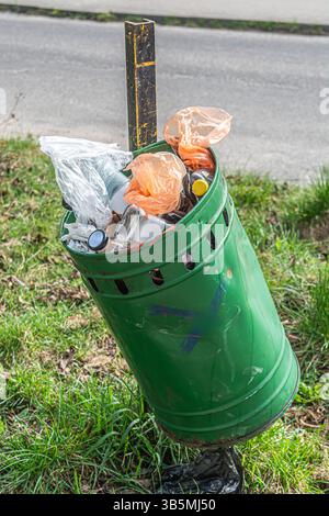 Überlaufender Mülleimer und Müll entlang des Weges verstreut. Stockfoto