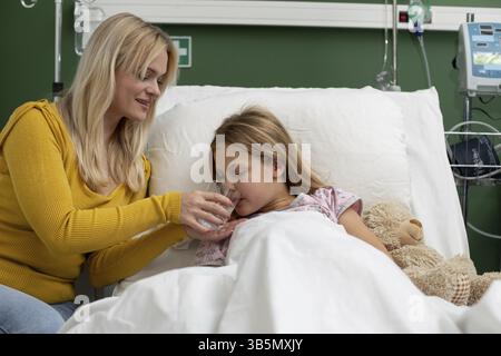 In einem Krankenhaus entfaltet sich ein berührender Moment zwischen einer hingebungsvollen Mutter und ihrer Tochter, der ihre tiefe Liebe widerspiegelt Stockfoto