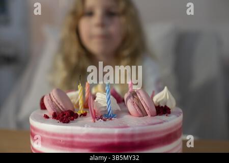 Ein wunderschöner Geburtstagskuchen, dekoriert mit lebhaften Macarons und bunten Kerzen, perfekt für Feiern Stockfoto