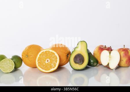 Genießen Sie eine bunte Auswahl an frischen Früchten wie saftige Orangen, pikante Limetten, cremige Avocado und knusprige Äpfel Stockfoto