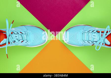 Rot, cyan, weiß, neue Tennisschuhe im Studio auf grünem, rosa, lila Hintergrund. Direkt von oben Stockfoto