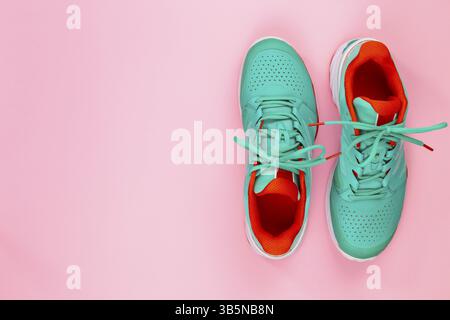 Rote, zyanblaue, weiße Tennisschuhe im Studio, auf rosa Hintergrund. Direkt von oben Stockfoto