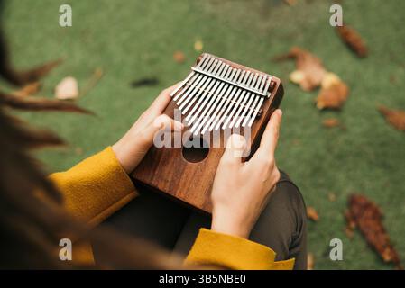 Nahaufnahme Frau, die auf der Terrasse im Herbst das Musikinstrument Kalimba oder Mbira spielt. Stockfoto