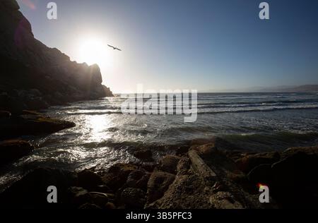 15. Juli 2022, Morro Bay, Kalifornien, USA: 15. Juli, 2022. ein Pelikan fliegt auf die untergehende Sonne unter dem Rocky Point in Morro Bay, Kalifornien. (Kreditbild: © Ralph Lauer/ZUMA Press Wire) Stockfoto