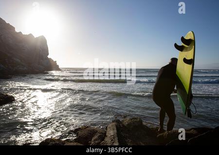 15. Juli 2022, Morro Bay, Kalifornien, USA: 15. Juli, 2022. ein Surfer klettert die Felsbrocken hinunter, als er am Rocky Point in Morro Bay, Kalifornien, aufbricht. (Kreditbild: © Ralph Lauer/ZUMA Press Wire) Stockfoto