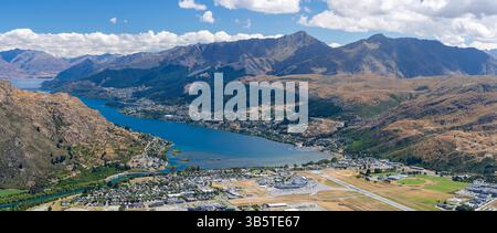 Blick auf Queenstown, Lake Wakatipu und den Flughafen Queenstown von der Straße zum Skigebiet Remarkables in der Nähe von Queenstown, Otago, Neuseeland. Stockfoto