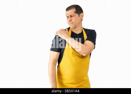 Hispanischer Mann, der seine Schulter berührt, mit gelber Schürze auf isoliertem weißem Hintergrund Stockfoto