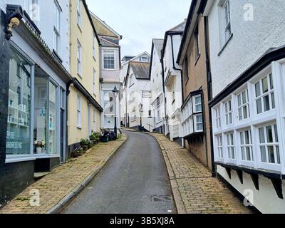 Die älteste Smith Street mit pastellfarbenen Wohngebäuden, alten Lampenpfosten und Kopfsteinpflaster im Kreuzfahrthafen von Dartmouth, Devon, Großbritannien Stockfoto