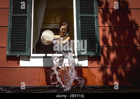 25. Juli 2022, es Castell, Balearen, Spanien: Eine Frau wirft während ihres Festivals in Sant Jaume Wasser auf Jung und Alt und nimmt an der traditionellen erfrischenden Wasserschlacht in einer zentralen Straße von es Castell Teil. Die wochenlange Hitzewelle wird voraussichtlich mit starken Nordwinden für Dienstag enden. (Foto: © Matthias Oesterle/ZUMA Press Wire) Stockfoto