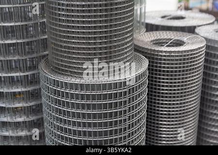 Rolle aus Metallgitter mit rechteckigen Zellen am Fenster eines Baugeschäfts. Industrie Stockfoto