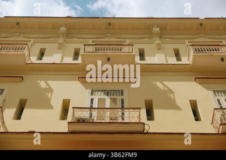 Flacher Blick auf die alte Kolonialarchitektur mit Balkonen in Old Havanna in Kuba. Licht und Schatten auf cremefarbenem Außenbereich des Gebäudes auf sunn Stockfoto