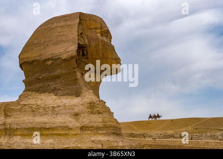 Die große Sphinx von Gizeh, Ägypten, mit drei Kamelreitern in der Ferne Stockfoto
