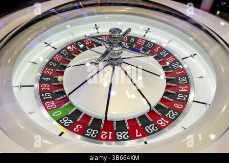 Moderner Roulette-Tisch im Kasino. Ball in der rotierenden Spielmaschine. Farbenfrohes Roulette-Rad Stockfoto
