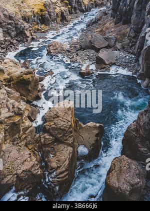 Verschlungener Gletscherfluss in der felsigen Schlucht in der Nähe des Hengifoss Wasserfalls im Osten Islands Stockfoto
