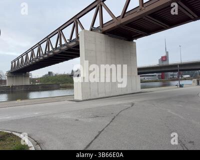 Nürnberg, Deutschland 2024 14. November: Hafen: Bild zeigt eine Stahlfachwerkbrücke über Betonpfeilern über einem Fluss. Eine Straße ist im Vordergrund. Über Stockfoto