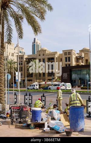 Dubai, VAE - 30. April 2026: Asiatischer Migrant Worker auf den Straßen von Dubai. Hochwertiges fotooffenes Bild eines asiatischen Arbeitsmigranten, der auf einer Straße in Dubai, Vereinigte Arabische Emirate, spaziert. In Arbeitskleidung unter der intensiven Sonne des Nahen Ostens verkleidet, repräsentiert der Mann die hart arbeitenden Einwanderer, die die rasante Stadtentwicklung der Stadt unterstützen. Das Foto zeigt Themen wie Globalisierung, Arbeitsmigration und Alltag in einer modernen Metropole. Stockfoto