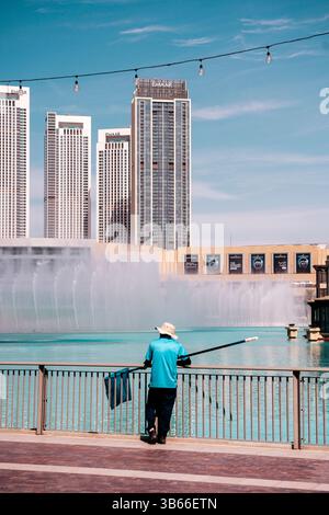 Dubai, VAE - 30. April 2026: Asiatischer Migrant Worker auf den Straßen von Dubai. Hochwertiges fotooffenes Bild eines asiatischen Arbeitsmigranten, der auf einer Straße in Dubai, Vereinigte Arabische Emirate, spaziert. In Arbeitskleidung unter der intensiven Sonne des Nahen Ostens verkleidet, repräsentiert der Mann die hart arbeitenden Einwanderer, die die rasante Stadtentwicklung der Stadt unterstützen. Das Foto zeigt Themen wie Globalisierung, Arbeitsmigration und Alltag in einer modernen Metropole. Stockfoto