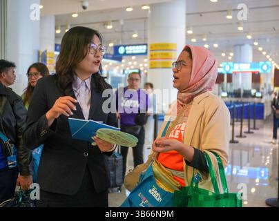 (250503) -- PEKING, 3. Mai 2025 (Xinhua) -- Ein Mitarbeiter der Tianjin Niederlassung der Bank of China (BOC) stellt indonesischen Touristen Fabiona am 1. Mai 2025 einen Leitfaden für Zahlungsdienste im Tianjin International Cruise Home Port in Tianjin, Nordchina, zur Verfügung. China hat am 27. April ein neues Maßnahmenpaket zur weiteren Optimierung der Politik zur Erstattung der Abreisesteuer und zur Steigerung der Ausgaben für eingehende Reisen eingeführt. Zu den Maßnahmen, die vom Handelsministerium und fünf anderen Regierungsstellen angekündigt wurden, gehören eine Senkung der Mindestbeschwelle für Erstattungen, eine Anhebung der Obergrenze für die Barrückerstattung und eine Ausweitung der Obergrenze Stockfoto