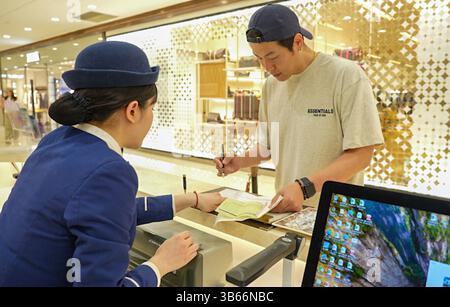 (250503) -- PEKING, 3. Mai 2025 (Xinhua) -- Ein Mitarbeiter (L) erbringt den Rückerstattungsservice für die Abreisesteuer für einen Touristen aus Südkorea an einem einkaufsplatz in der südwestchinesischen Gemeinde Chongqing, 11. April 2025. China hat am 27. April ein neues Maßnahmenpaket zur weiteren Optimierung der Politik zur Erstattung der Abreisesteuer und zur Steigerung der Ausgaben für eingehende Reisen eingeführt. Zu den Maßnahmen, die vom Handelsministerium und fünf anderen Regierungsstellen angekündigt wurden, gehören die Senkung der Mindestschwelle für Rückerstattungen, die Anhebung der Obergrenze für Barrückerstattungen, die Erweiterung des Netzes teilnehmender Geschäfte und die Erhöhung der Mindestschwelle für Rückerstattungen Stockfoto