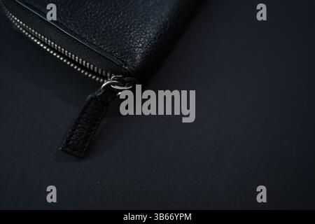 Minimalistisches schwarzes Ledermappe mit Reißverschluss – Nahaufnahme auf dunklem Hintergrund Stockfoto