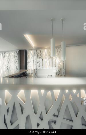 Moderner Hotelrezeptionstresen mit abstrakten geometrischen Designelementen, sanfter Beleuchtung und minimalistischen Pendelleuchten schaffen ein elegantes und elegantes Ambiente Stockfoto