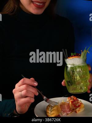 Frau genießt Vorspeisen und einen grünen Cocktail Stockfoto