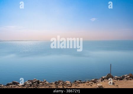 Der weitläufige Blick auf das ruhige blaue Wasser des Assuan High Dam Stausees in Ägypten stand im Kontrast zu einem felsigen, trockenen Ufer an einem Frühlingsmorgen. Stockfoto